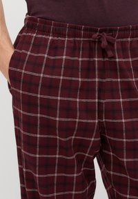 Burgundi ruudulised pidžaamapüksid valge ruudustikuga, elastne vöökoht ja pael. Pehme tekstuur ning küljetaskud mugavuseks.
