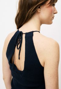 Navy gehäkeltes Halftertop mit offenem Rücken, ausgestattet mit einem Bindeband am Hals. Der Stoff hat eine strukturierte, gestrickte Optik.