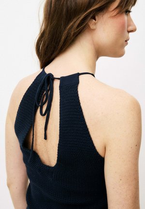 Haut halter au crochet marine avec un dos ouvert, présentant une fermeture à nouer autour du cou. Le tissu a une apparence texturée et tricotée.