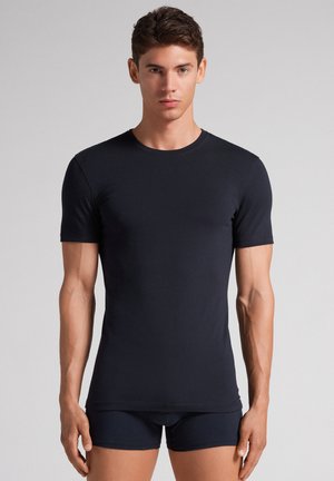 Marineblaue Kurzarm-T-Shirt aus glattem Stoff, mit Rundhalsausschnitt und enganliegendem Design, kombiniert mit dunklen Shorts.