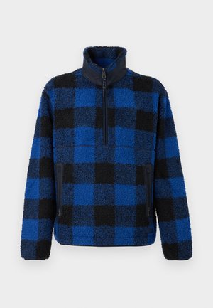 Pullover in pile con colletto alto, caratterizzato da un motivo a quadri blu e neri, zip frontale e tasche laterali con zip. Texture morbida.