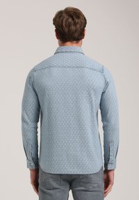 Lichtblauwe denimshirt met een subtiele patroonstructuur, knoopmanchetten en een rechte zoom, ontworpen met een klassieke kraag.