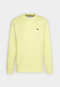 Gul crewneck sweatshirt i bomullsblandad tyg, med en liten grön broderad logotyp på vänster bröst och ribbade ärmslut.