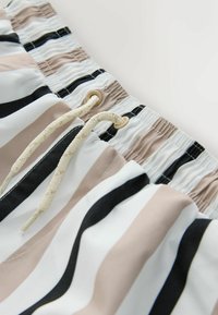 Bañador corto con rayas verticales en tonos beige, negro y blanco. Cuenta con cierre de cordón con ojales beige y tela texturizada.