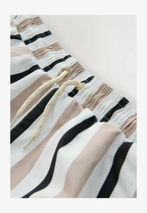 Short de bain à rayures verticales dans des tons beige, noir et blanc. Dispose d'une fermeture à cordon avec des œillets beiges et un tissu texturé.