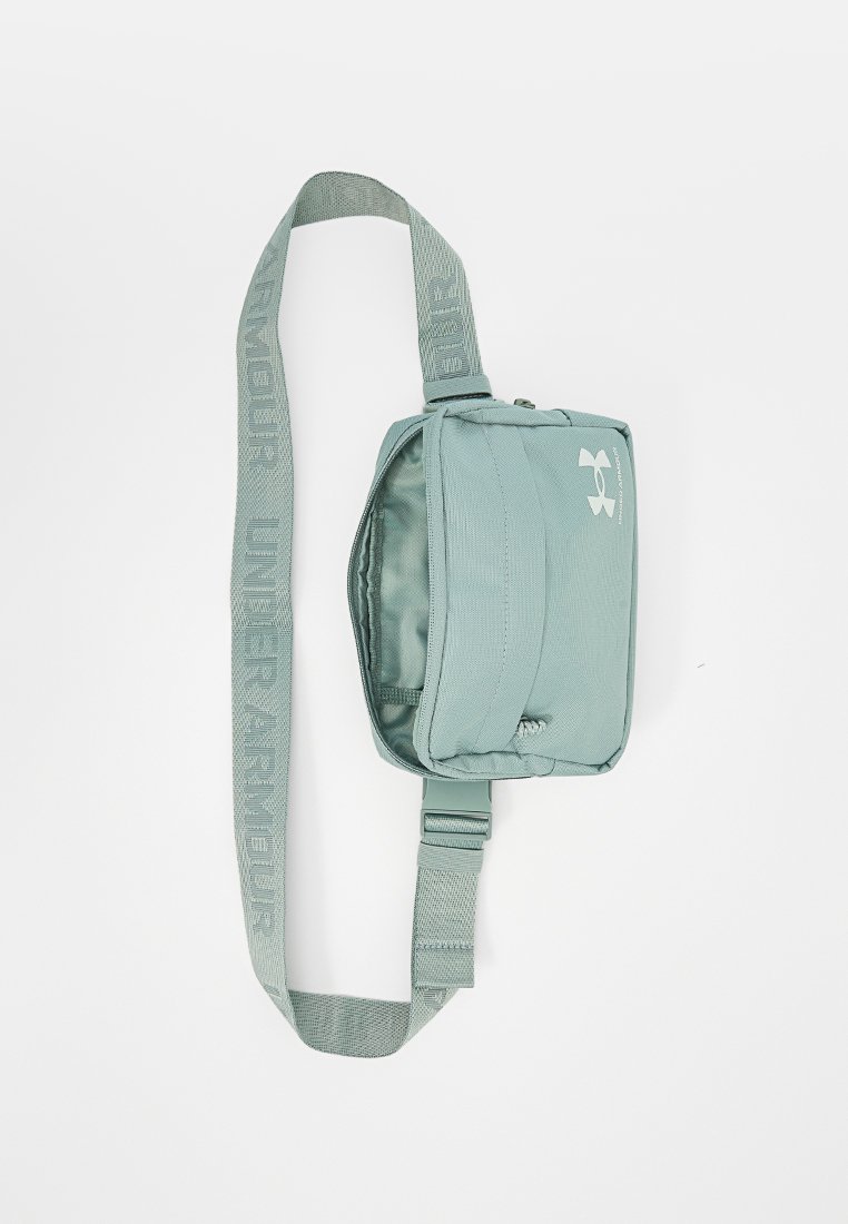 Bolso bandolera verde claro de Under Armour con correa ajustable y compartimento principal con cremallera, logo visible en el frente.