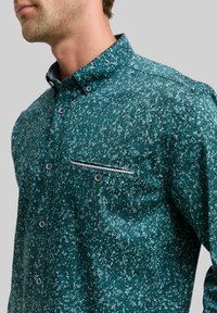 Patroon overhemd in teal met een gestructureerde stof, voorzien van een borstzak versierd met een contrasterende streep en zwarte knopen.