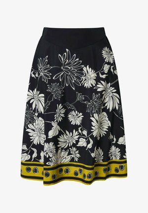 Jupe trapèze noire avec grand imprimé floral blanc et bordure jaune ornée de pois noirs le long de l'ourlet.