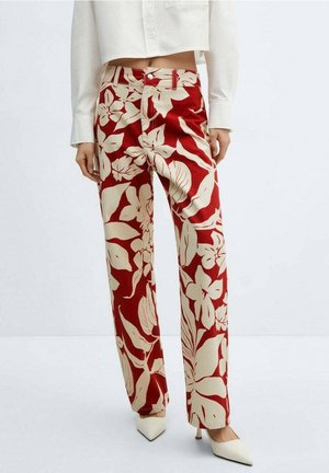 Rote und beige Blumenmuster-Hose mit geradem Bein, getragen mit einem kurzen weißen Shirt und weißen spitzen High Heels.