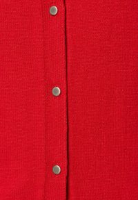 Czerwony, dziany kardigan o fakturowanej tkaninie, z srebrnymi zatrzaskami z przodu. Gładka faktura w jednolitym kolorze.