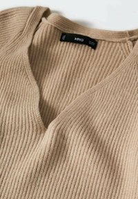 Beige geripptes Strickpullover mit einem V-Ausschnitt und subtiler Textur. Mit einem schwarzen Markenetikett innen am Ausschnitt.