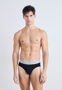 Zwarte boxershorts met een grijze Calvin Klein-logo tailleband, gemaakt van een zachte, elastische stof en met een aansluitende fit, gepresenteerd door een mannelijk figuur.