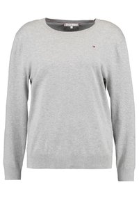 Šedý pletený svetr s kulatým výstřihem, dlouhými rukávy a malým logem na hrudi. Má měkkou texturu a žebrované manžety a lem.