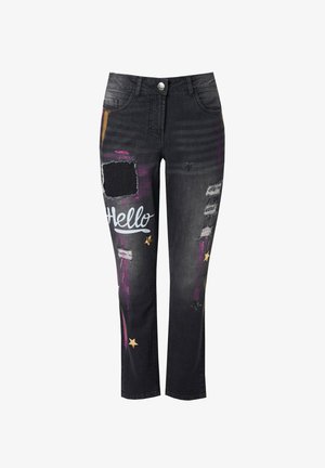 Vaqueros de mezclilla negra con corte recto, que presentan salpicaduras de pintura coloridas, parches desgastados y la palabra "Hola" en azul cerca de la zona de la cadera.