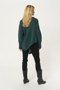 Maglione oversized teal lavorato a maglia con un motivo zigzag testurizzato, maniche lunghe e orlo curvo, abbinato a pantaloni neri aderenti e stivali da cowboy neri.