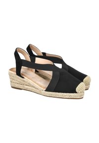Zapatos de cuña de ante negro con suela de yute trenzado, abertura en la parte trasera y tiras cruzadas. Punta redondeada con un acento trenzado de color claro.