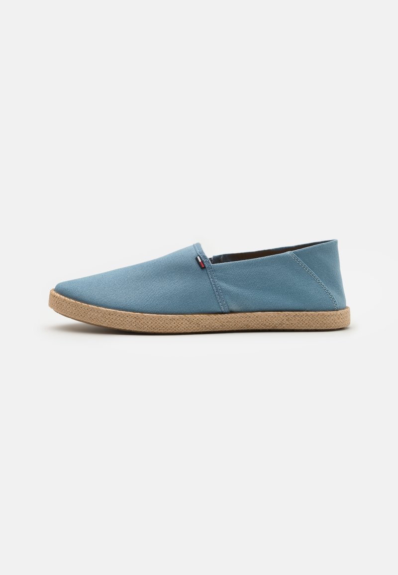 Chaussure décontractée à enfiler avec dessus en tissu bleu clair et semelle tannée tissée, vue de profil sur fond blanc.