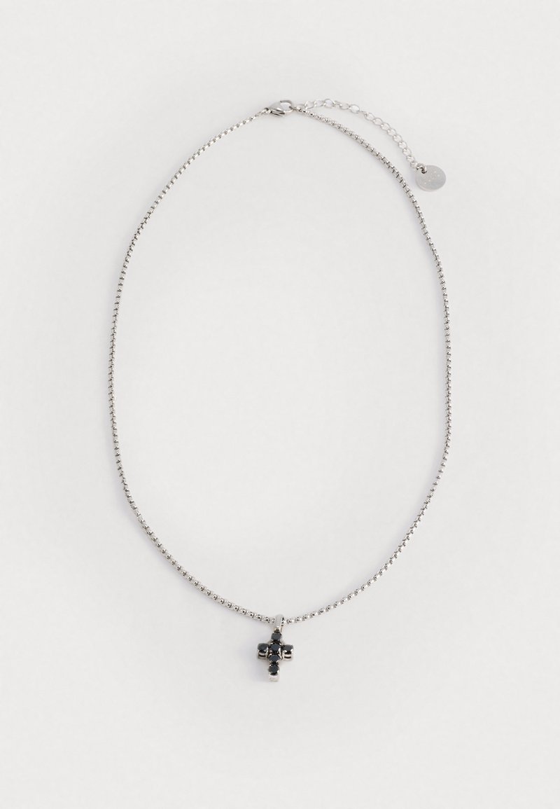 Ασημένιο κολιέ με λεπτή αλυσίδα, στολισμένο με ένα μικρό μαύρο γοτθικό σταυρό. Λεπτή λάμψη και ευαίσθητος σχεδιασμός.