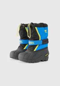 Hőszigetelt téli csizmák fekete és kék nylon felsőrésszel, gumitalppal, amely textúrázott tapadást biztosít, és élénk sárga elasztikus húzózsinórral.