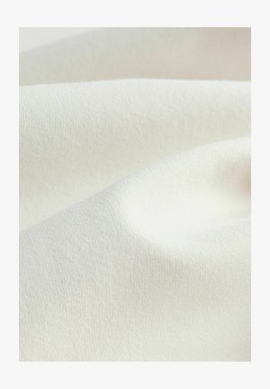 Matériau textile dans une teinte crème, présentant une surface lisse légèrement texturée avec des plis doux, affichant une apparence uniforme et subtile.