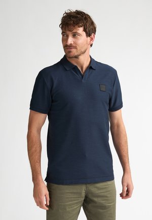 Granatowa koszulka polo z krótkimi rękawami, teksturowaną tkaniną i naszywką na piersi. Dopasowany fason z klasycznym kołnierzykiem i bocznym rozcięciem ułatwiającym ruch.