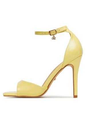 Sandale à talon haut jaune avec une finition en cuir lisse, design à bout ouvert, bride fine autour de la cheville avec une boucle dorée, et talon aiguilles élancé.