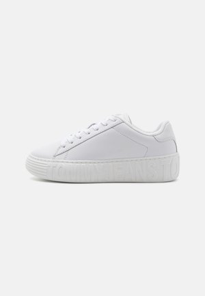 Białe syntetyczne sneakersy z płaskim, zaokrąglonym noskiem, teksturowaną podeszwą i tłoczonym logotypem na boku. Z wężykowym zapięciem i wyściełanym kołnierzem.