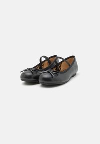 Bailarinas negras de cuero liso, con punta redondeada, detalle de lazo y diseño de dos correas. El interior presenta un estampado de leopardo.