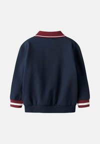 Tumesinine bomber-jakk maroon ribivarrukaga, valgete triipudega varrukatel ja elastse äärega, mis tagab mugava istuvuse.