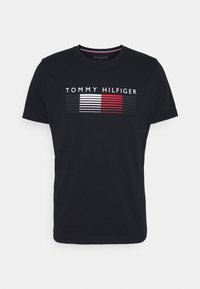 Czarny bawełniany t-shirt z białym i czerwonym logo w paski. Okrągły dekolt i krótkie rękawy o gładkiej fakturze.