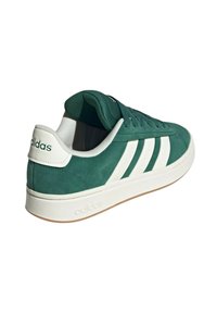 Sneaker verde in suede con dettagli in pelle bianca, caratterizzato da tre strisce bianche e una suola bianca. Design classico con chiusura a lacci.