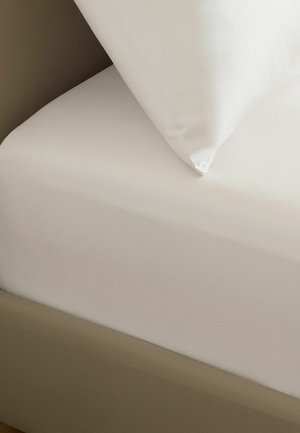 Weißes Kissen, das auf einem ordentlich gemachten beigen Bett mit glattem Spannbettlaken und passendem Bettrahmen liegt.