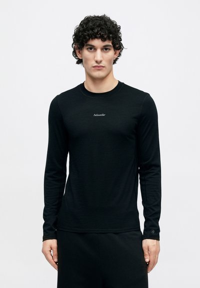 Čierne tričko s dlhými rukávmi vyrobené z hladkej, ľahkej látky s malým logom na hrudi a priliehavým strihom.