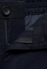 Námořnická modrá látka na oděvy s knoflíkovým zapínáním a zipem, která má jemnou texturu a decentní štepování po obvodu pasu.