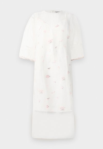 Fehér ruha rövid puffos ujjakkal, függőleges redőkkel és apró rózsaszín virágmintákkal. Könnyű anyagból készült, réteges kialakítással.