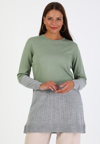 Langärmlige Tunika in Hellgrün und Grau. Strickstruktur, runder Halsausschnitt und gerippte Akzente. Verfügt über ein plissiertes Design am Saum.