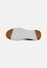 White sneaker sole with a textured rubber surface, featuring a brown accent on the toe, and a grid pattern for traction.