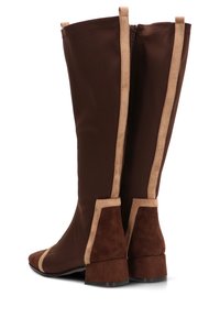 Botas marrones hasta la rodilla con cuerpo de tela lisa, detalles de ante beige, tacones cuadrados y cierre de cremallera en la parte trasera.