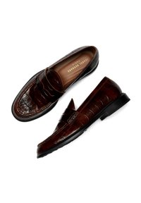 Bruine loafers van geperforeerd leer met een vlakke zwarte zool, met een voorste banddetail en een gladde voering.