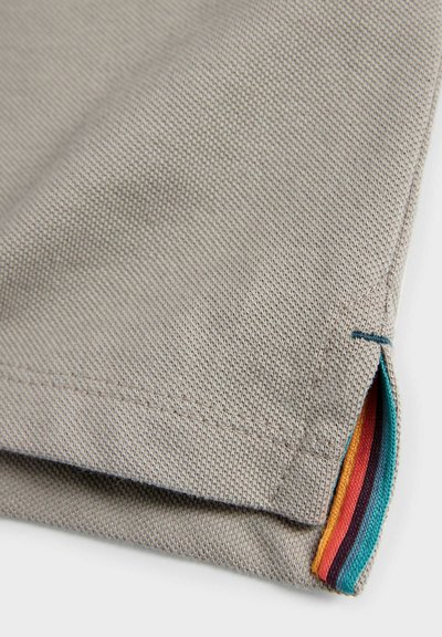 Sivý textil s textúrovaným povrchom, s preloženým okrajom a farebnými akcentovými pruhmi v červenej, modrej, oranžovej a purpurovej farbe na leme.