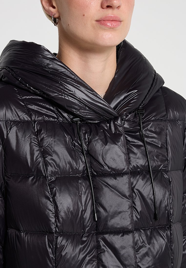 Flauschige schwarze Jacke mit großer Kapuze, glänzende gesteppten Textur, Kordelzüge am Hals, in modernem, kastiger Design und minimalem Zubehör.