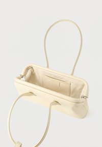 Ορθογώνια κρεμ δερμάτινη τσάντα χειρός με λεπτές λαβές, ανοιχτό πάνω μέρος και εσωτερικό από μπεζ ύφασμα με μια μικρή εσωτερική θήκη.