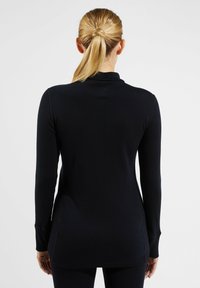 Schwarzes Langarmshirt mit einem Stehkragen, glatter Textur und einem längeren hinteren Saum. Hat enge Ärmel und Seitenschlitze für Bewegungsfreiheit.