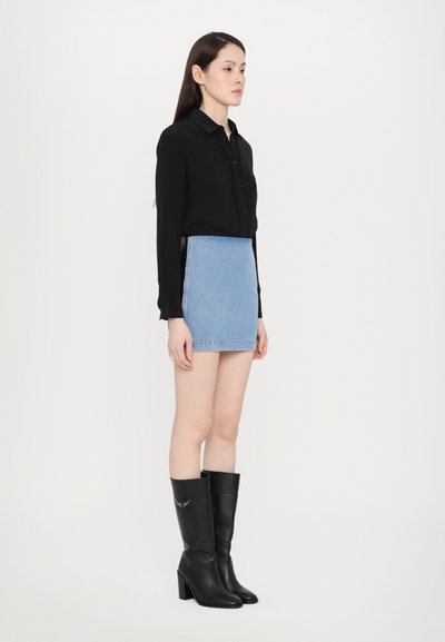 Black long-sleeve blouse, light blue denim mini skirt, and knee-high black boots with block heels. Smooth textures and fitted design.