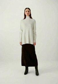 Light gray turtleneck sweater paired with a long brown skirt. The outfit features a relaxed fit and soft texture, complemented by black boots.