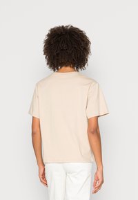 Béžové bavlněné tričko s krátkými rukávy a kulatým výstřihem, s volným střihem a hladkou texturou. Zadní pohled, bez vzorů nebo grafik.