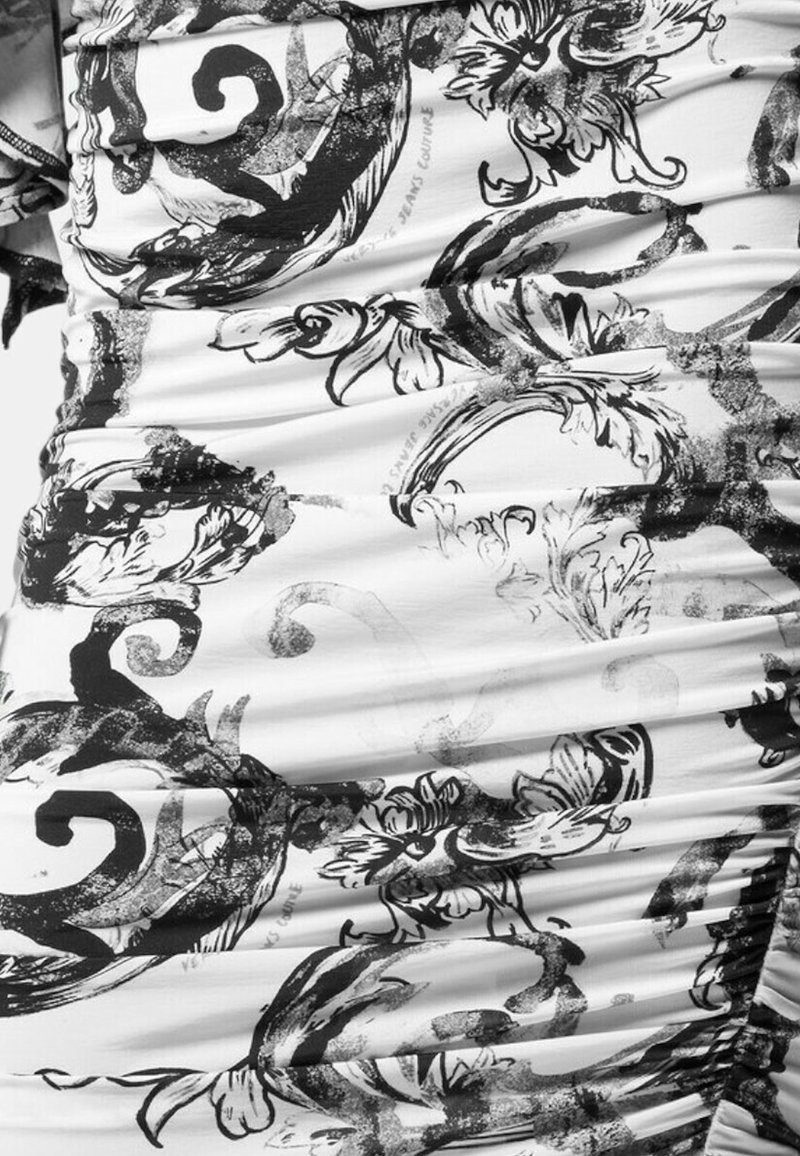 Weißer Stoff mit schwarzen floralem Muster und Wirbelmustern, der Raffung aufweist, die Textur und Falten für eine taillierte Optik erzeugt.