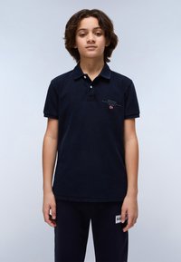 Mörkblå pikétröja med korta ärmar, krage och broderad logotypdetalj på bröstet. Tyget har en strukturerad yta.