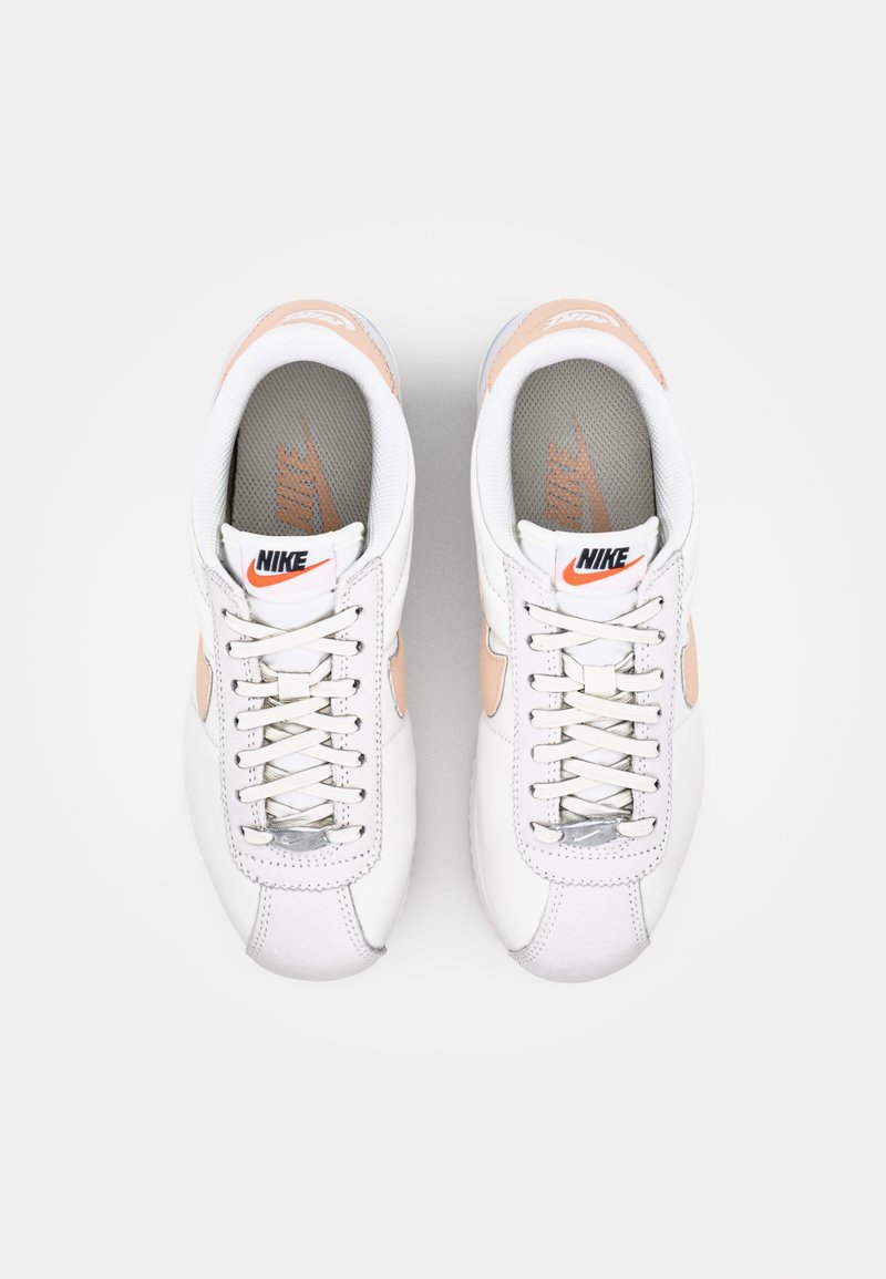 Baskets en cuir blanc avec des accents orange, des détails en argent et une semelle intérieure texturée grise. Présente un design classique à lacets et un bout arrondi.