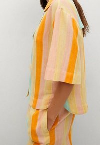 Kurzärmliges Hemd mit Kragen aus leichtem Baumwollstoff mit breiten Pastellstreifen (rosa, orange, gelb, blau). Verfügt über eine lockere Passform und Seitentaschen.